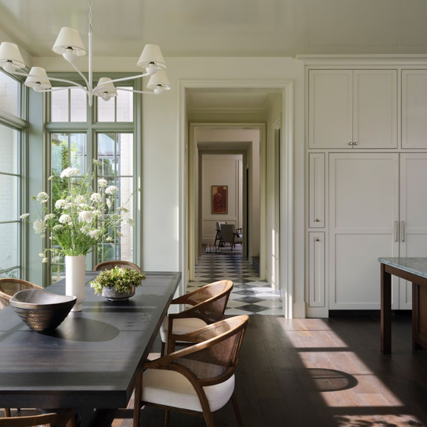 Elegant dining area with large windows, dark table, chairs, and chandelier, leading to a hallway.