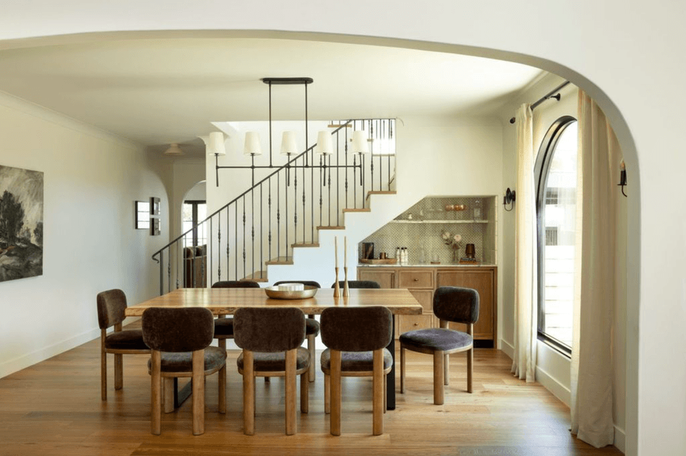 Elegant dining area with wooden table, six chairs, and a staircase in the background.