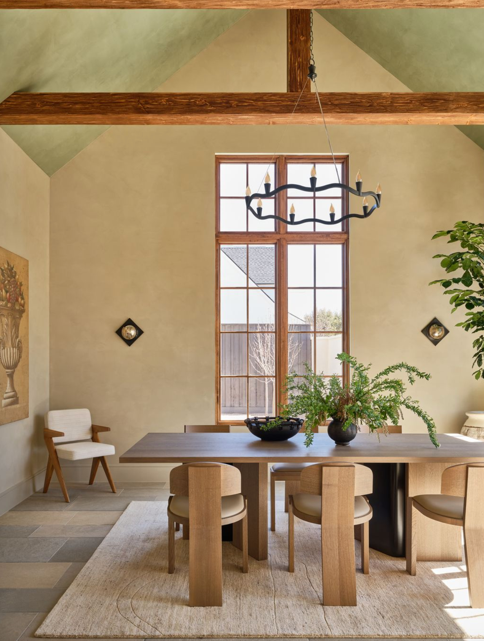 Elegant dining room with wooden table, chairs, a chandelier, and large window.