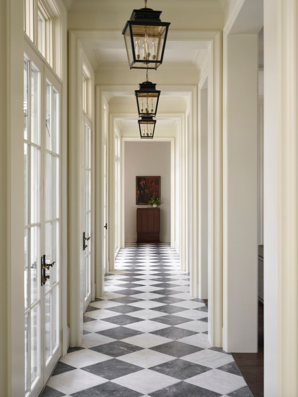 Elegant hallway with checkered floor, lantern lights, and tall windows.