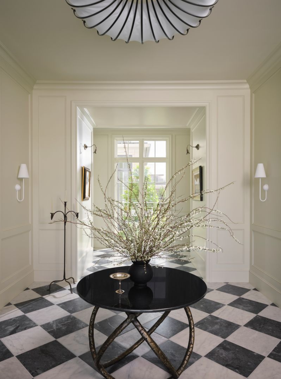 Elegant hallway with checkered floor, round table, and floral centerpiece.