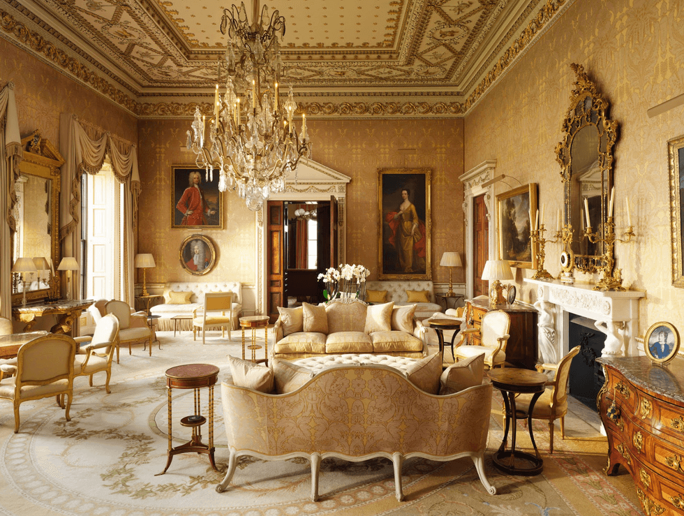 Elegant, luxurious room with ornate furniture, chandeliers, gold accents, and framed portraits.