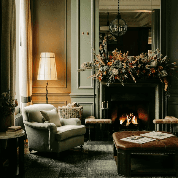 Elegant room with fireplace, armchair, green walls, and floral mantelpiece.