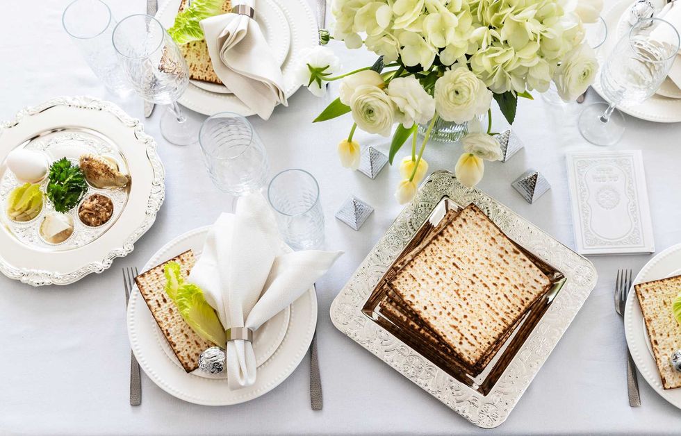 Elegant Seder table setup with matzo, seder plate, and white floral centerpiece.