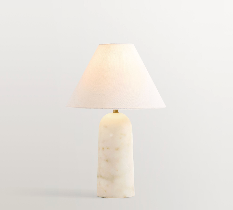 Elegant table lamp with a warm-colored shade and marble base against a plain background.