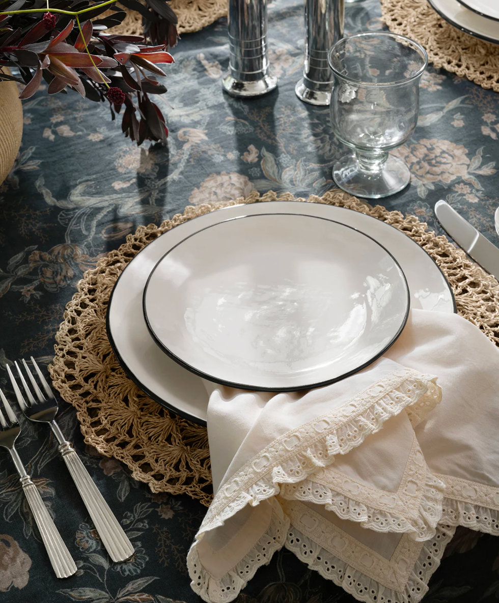 Elegant table setting with plates, lace napkin, and floral tablecloth.