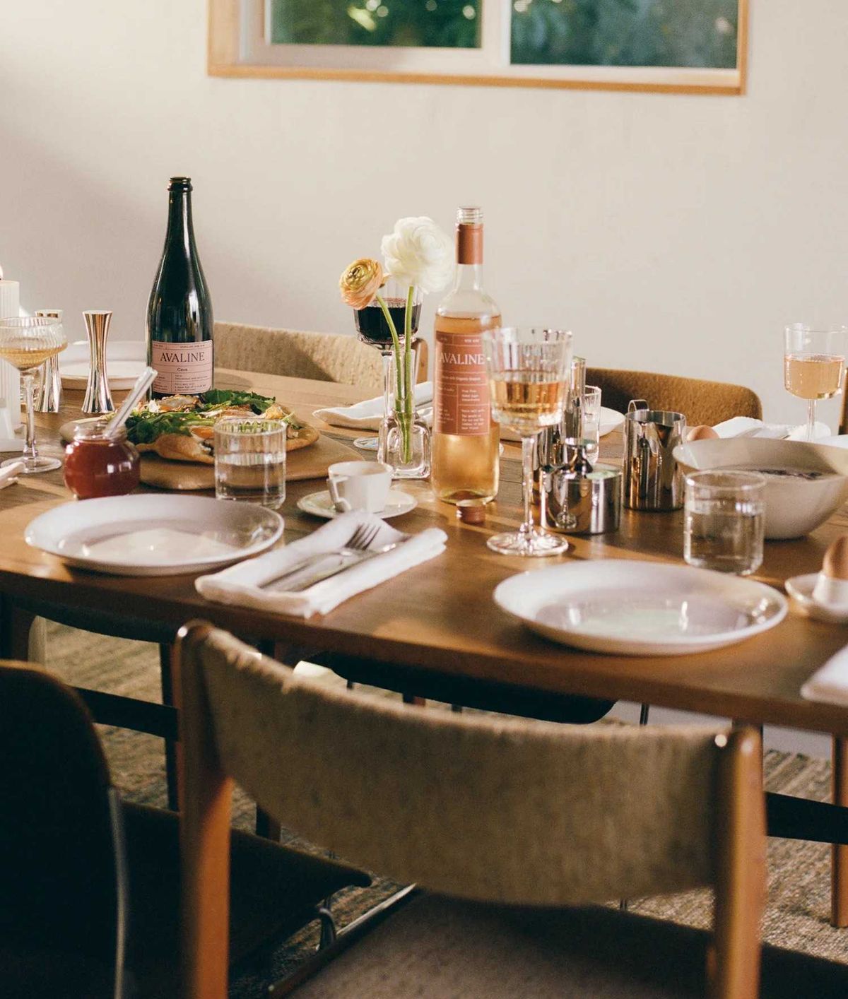 Elegant table setting with wine, pizza, flowers, and glassware.