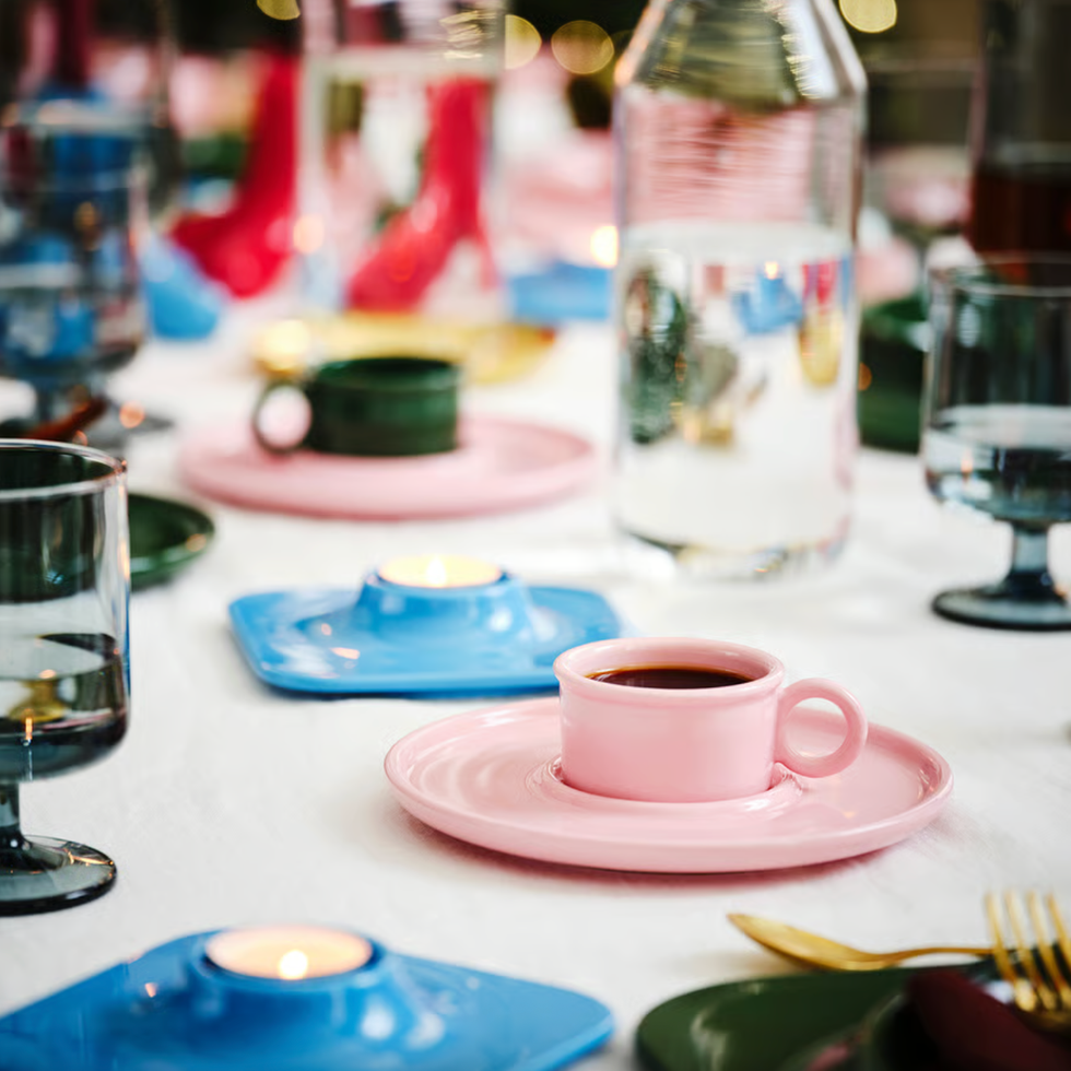 Elegant table with pink cups, blue candle holders, and glassware on a white cloth.