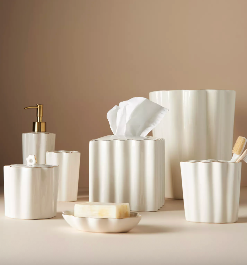 Elegant white fluted bathroom accessories with gold accents on a beige background.