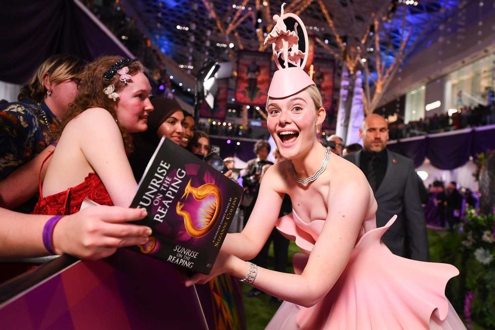 elle fanning signing a copy of sunrise on the reaping by suzanne collins at the recent hunger games premiere