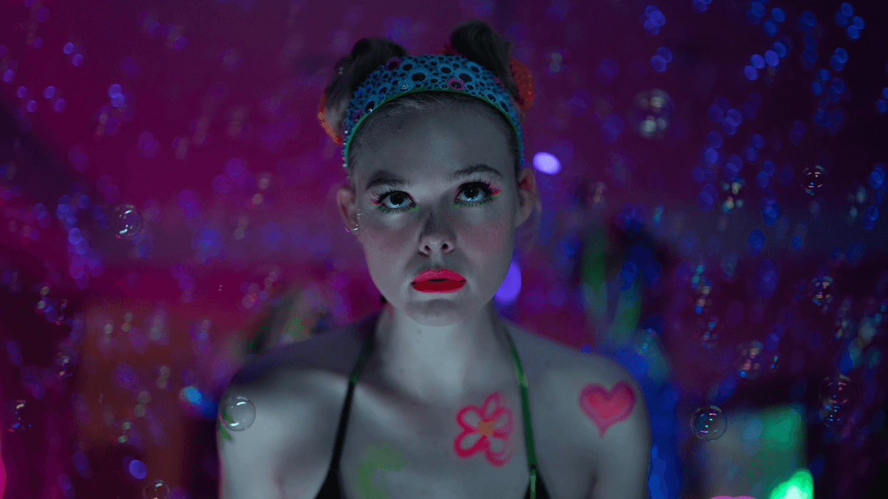 Elle Fanning sporting a neon makeup look and space buns in a dreamy, colorful setting for Apple TV+'s Margo's Got Money Troubles.