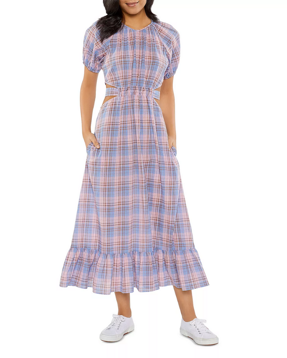 model wears pink and blue plaid tiered dress with white sneakers