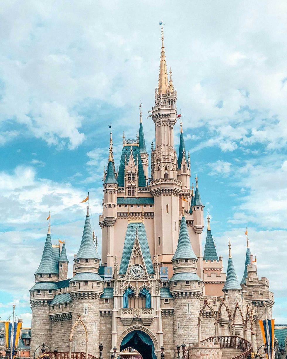 Fairy-tale castle with towers against a bright blue sky with clouds.