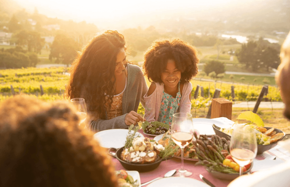 Family enjoying a picnic with vineyard views at sunset.