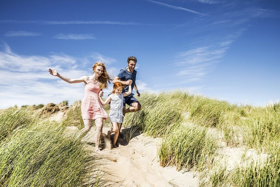 Family running over dunes.
