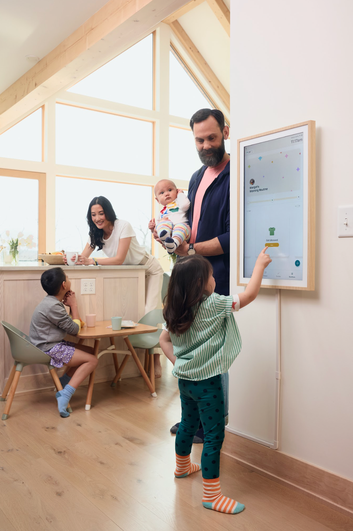 Family with kids interacting with a wall-mounted digital display at home.