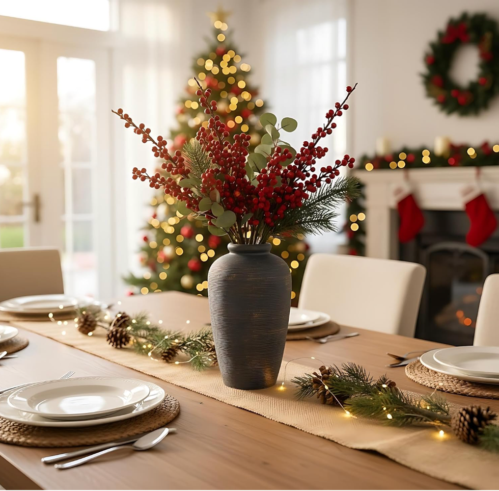 Festive dining table with a vase, holiday greenery, and Christmas lights.