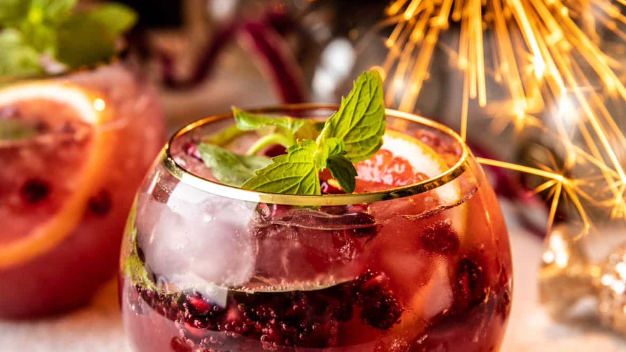 Festive drink with fruit, mint, and sparkler; surrounded by lights and decorations.