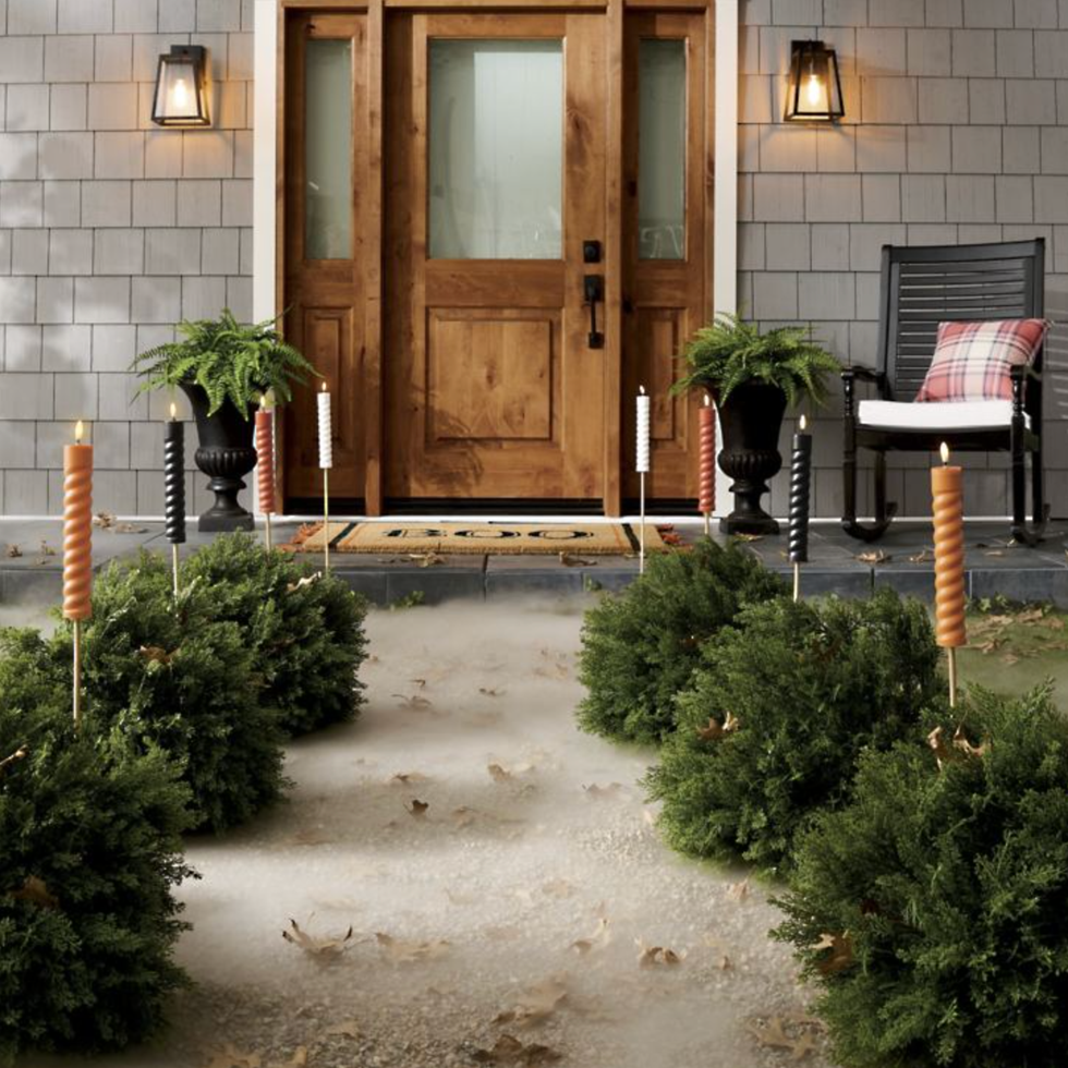 Festive porch with candles, greenery, and a wooden door, flanked by a rocking chair.