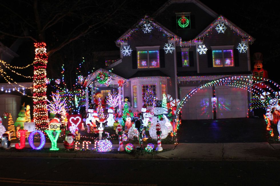 Festively decorated house with colorful Christmas lights and ornaments at night.