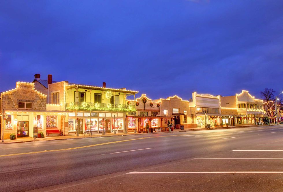 Festively lit downtown street with shops, decorated for the holidays at dusk.