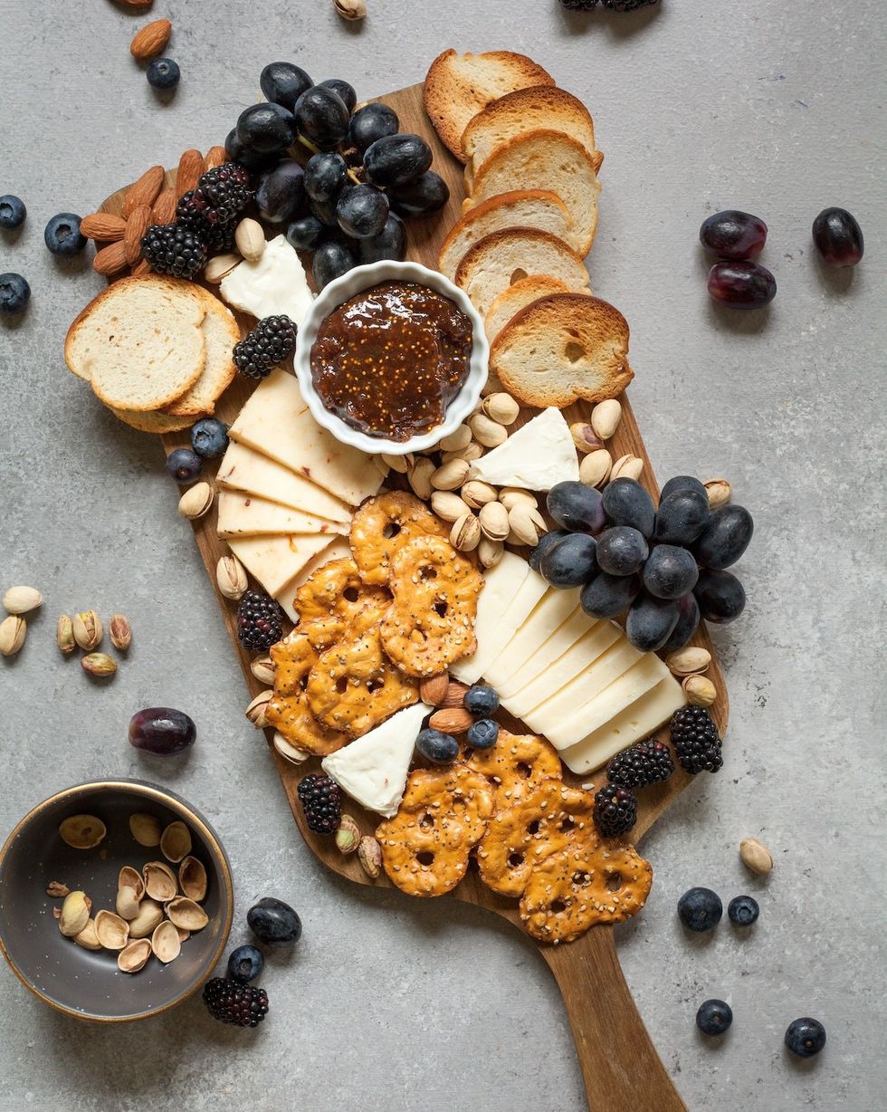 fig jam on a cheese board with berries, pretzels, and nuts