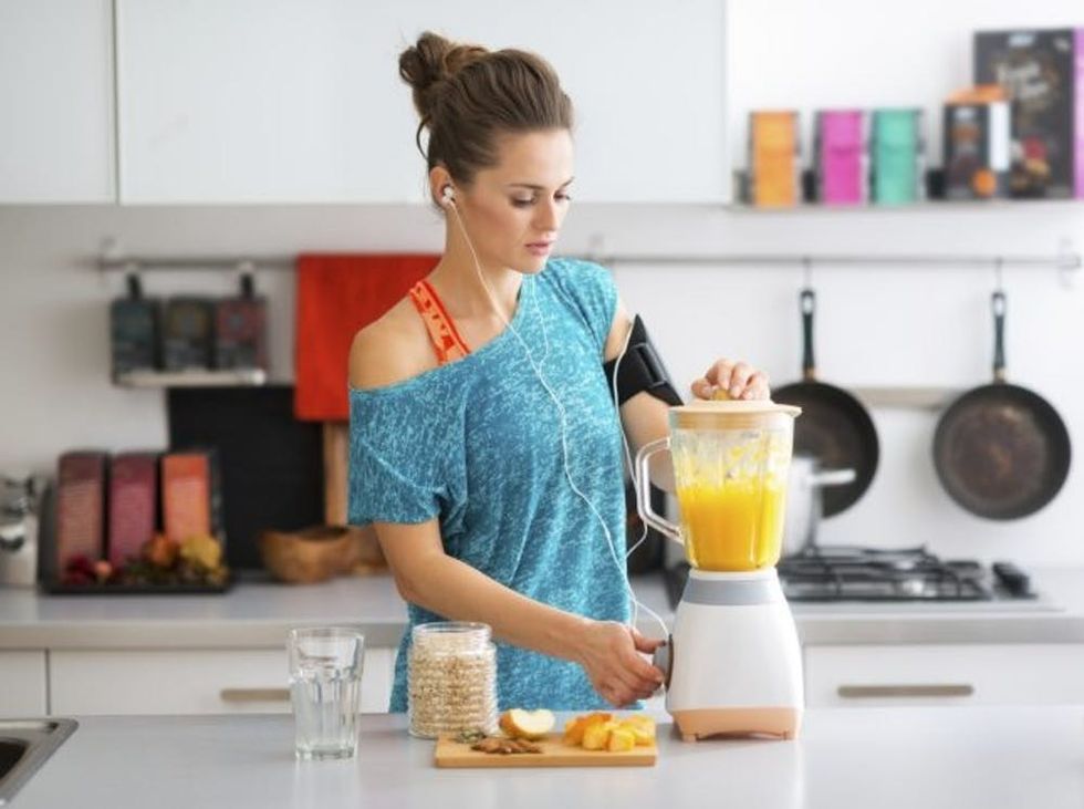 Fit woman in kitchen making a smoothie workout fitness