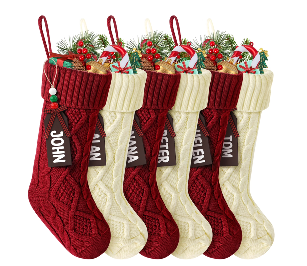Five festive stockings filled with gifts and greenery, personalized with tags.