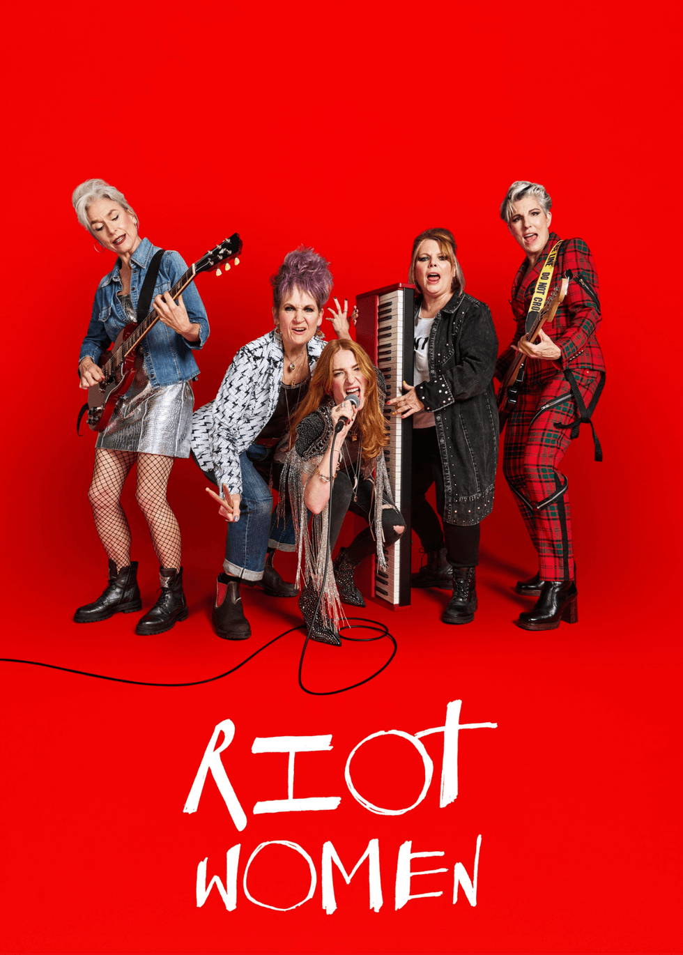 Five women in a band pose energetically against a red background. "RIOT WOMEN" text below.
