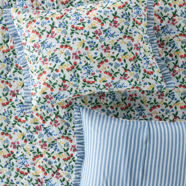 Floral and striped bedding with blue and white ruffled edges.