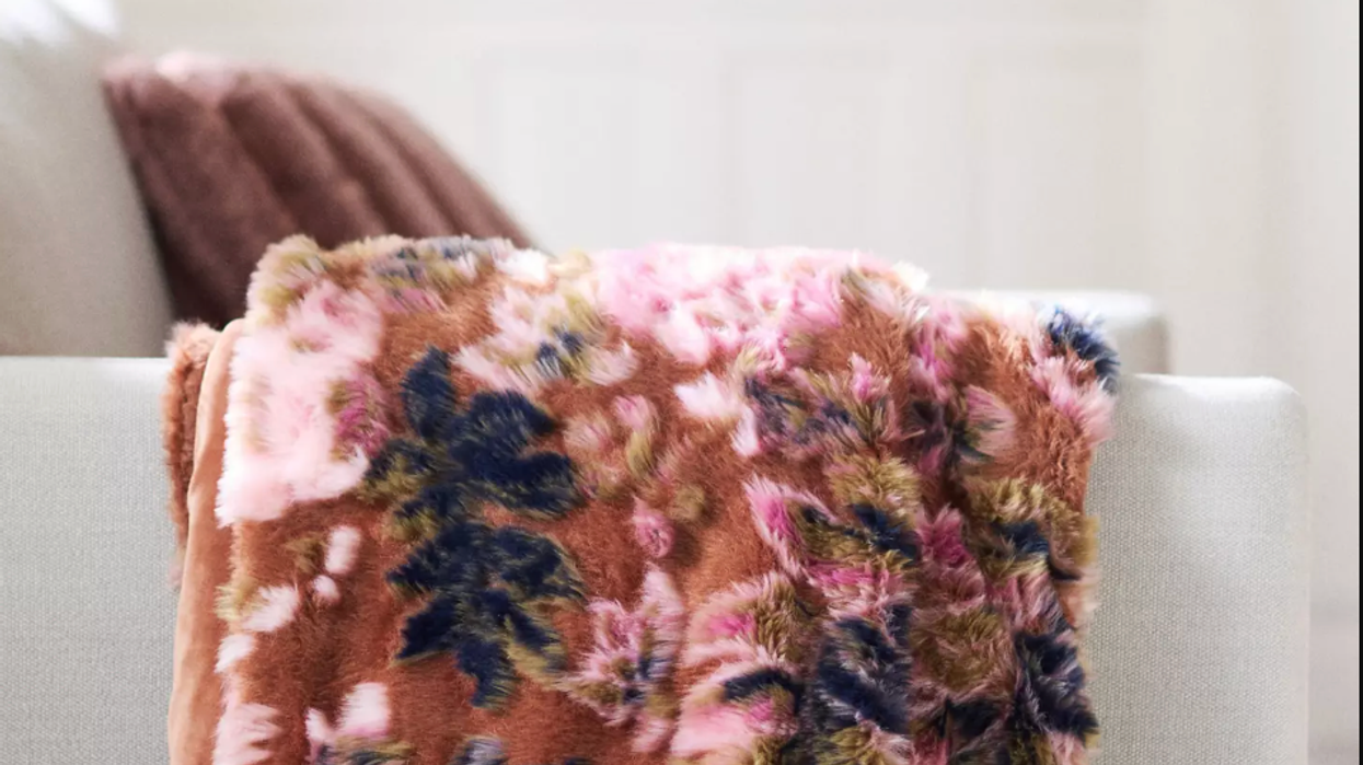 Floral-patterned, plush blanket draped over white sofa in cozy room.