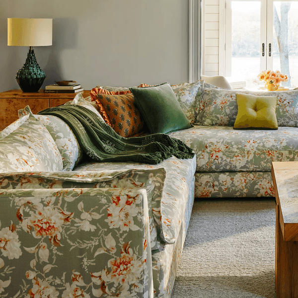 Floral-patterned sofa with colorful cushions in a bright living room by the window.