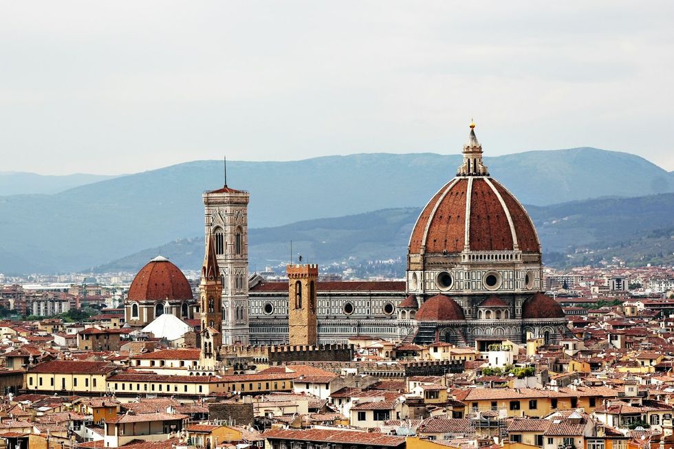 Florence's iconic cathedral with red dome and mountains in the background.