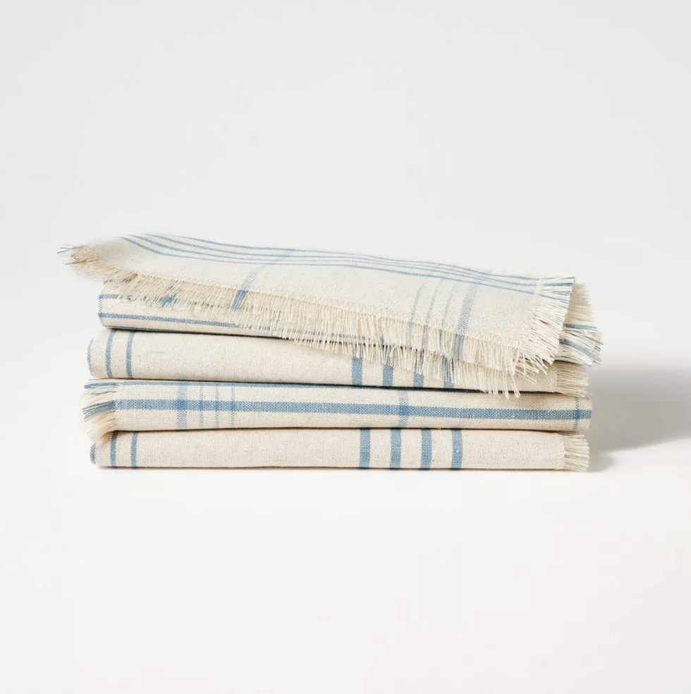Folded beige and blue striped fabric with fringed edges on white background.