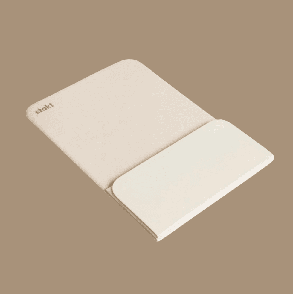 Folded beige yoga mat on a brown background.