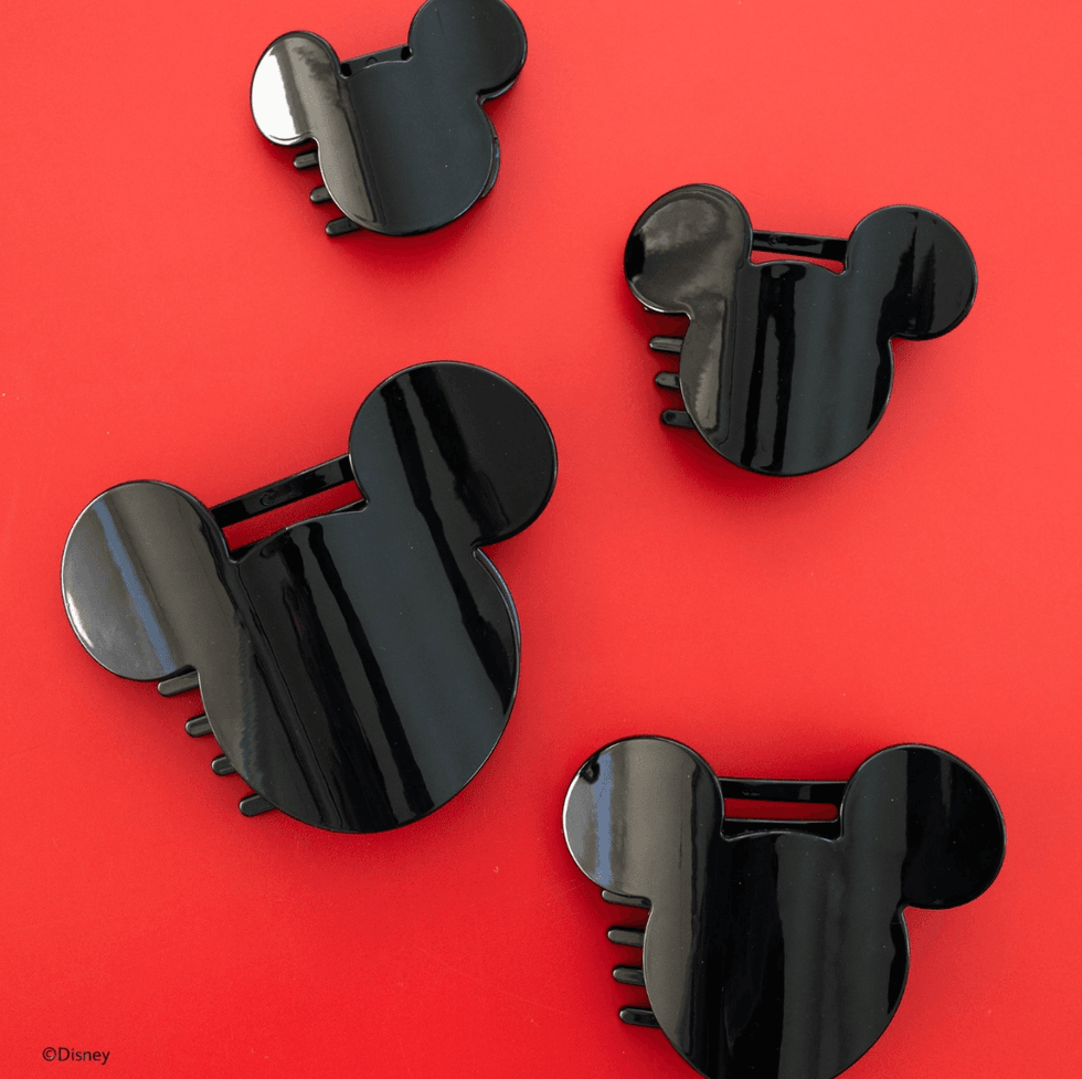 Four black Mickey Mouse hair clips on a red background.