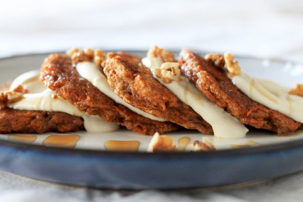 Four carrot cake pancakes with lime cashew cream rest on top of one another.