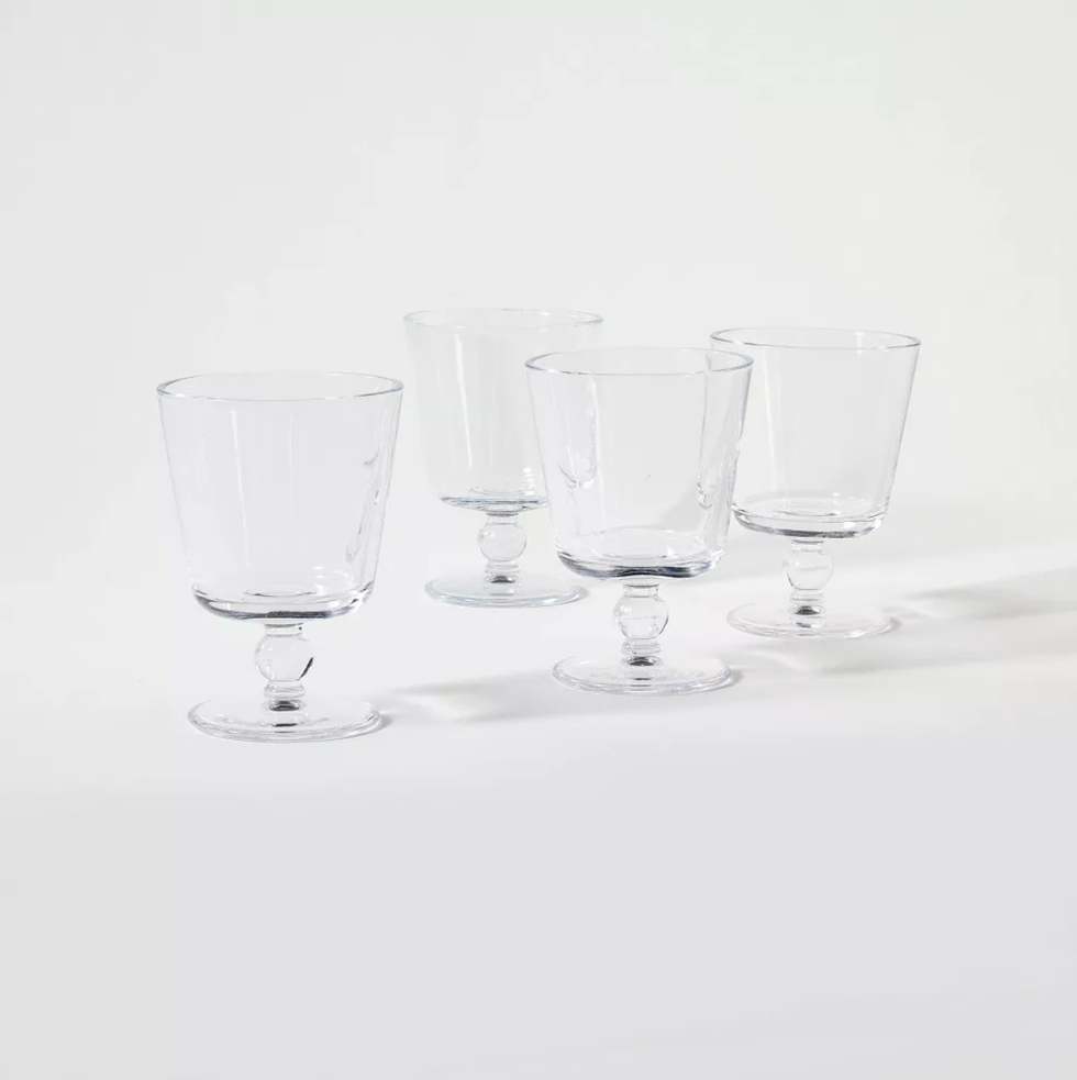 Four clear, stemmed glasses on a white surface.