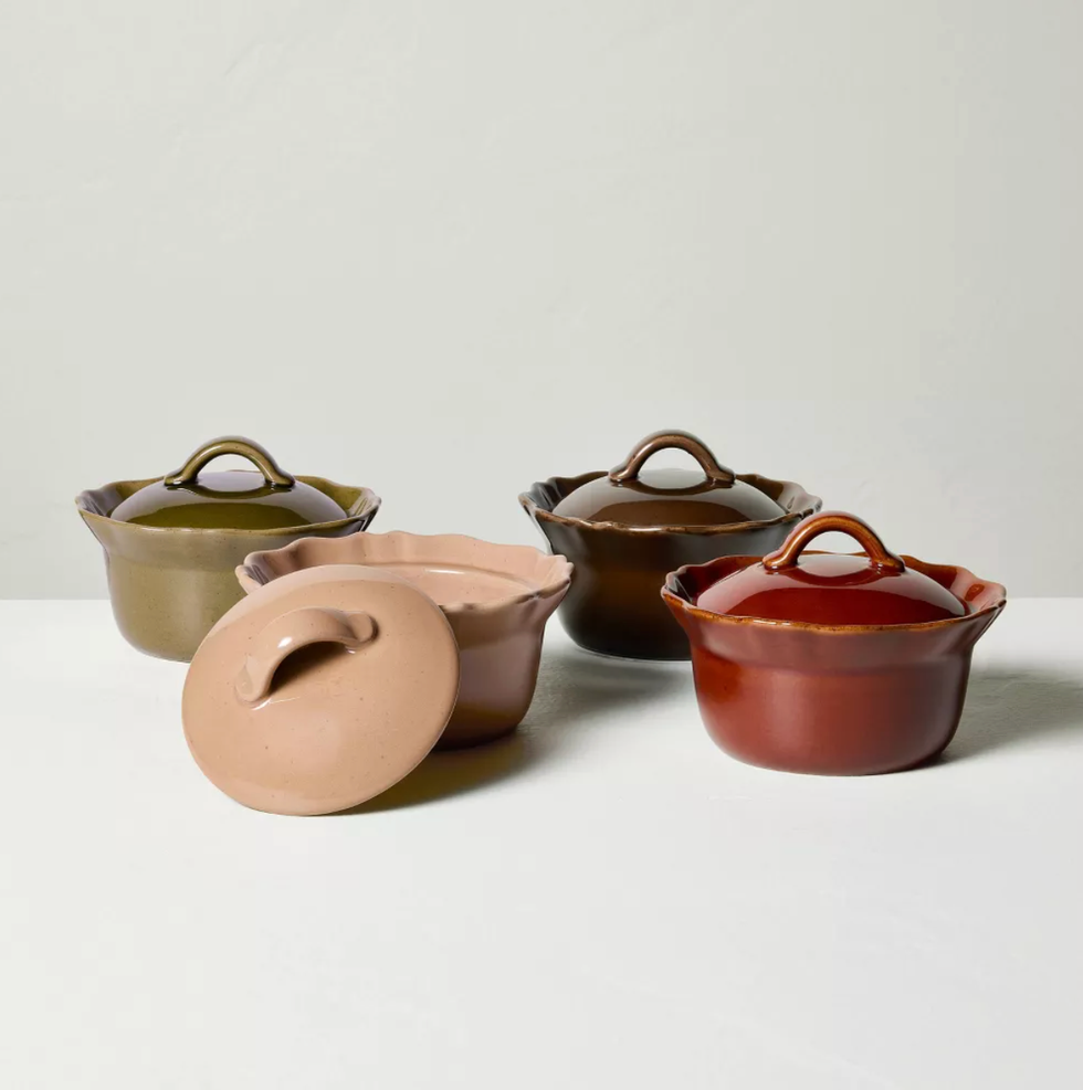 Four colorful ceramic pots with lids, one open, on a white surface.