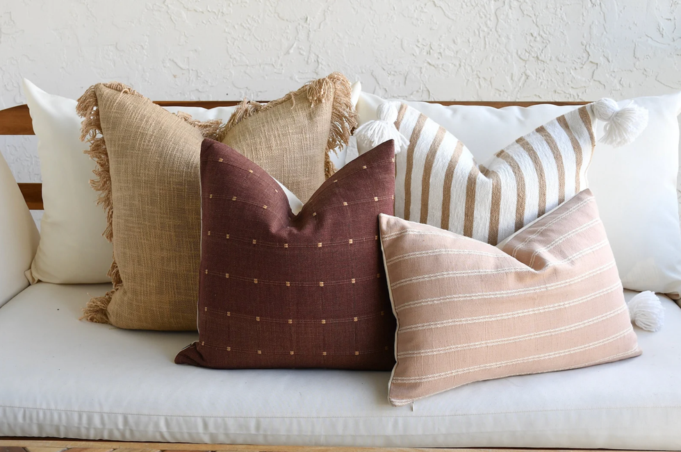 Four decorative pillows on a white sofa with varying textures and patterns.
