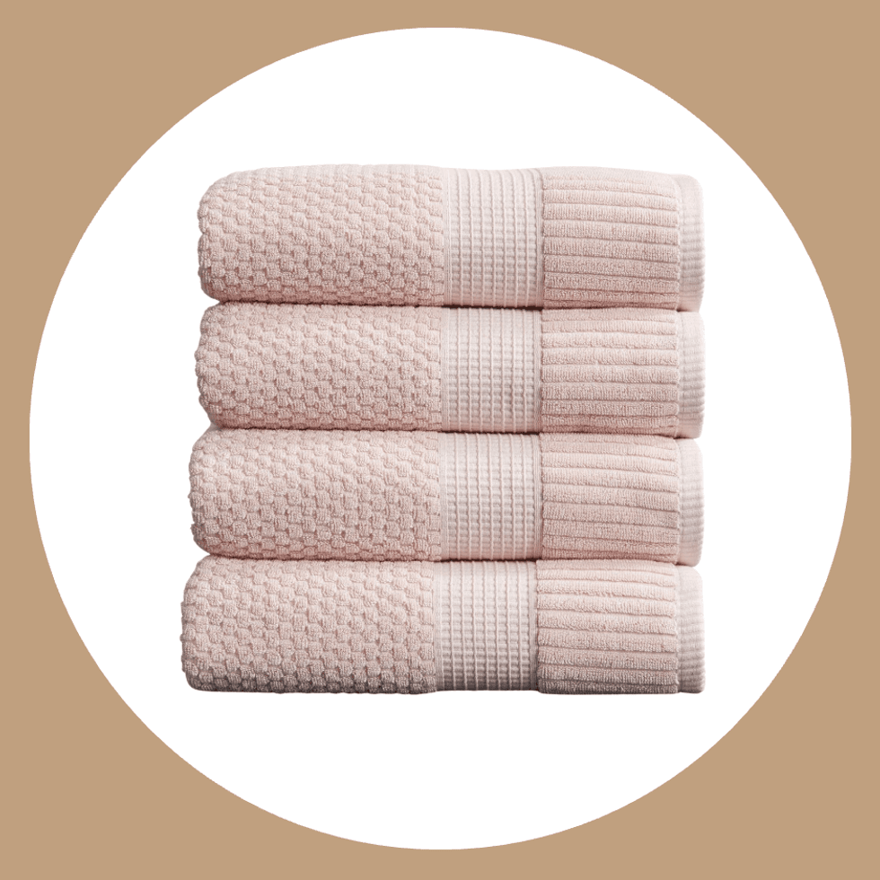 Four folded pink towels stacked neatly on a beige background.