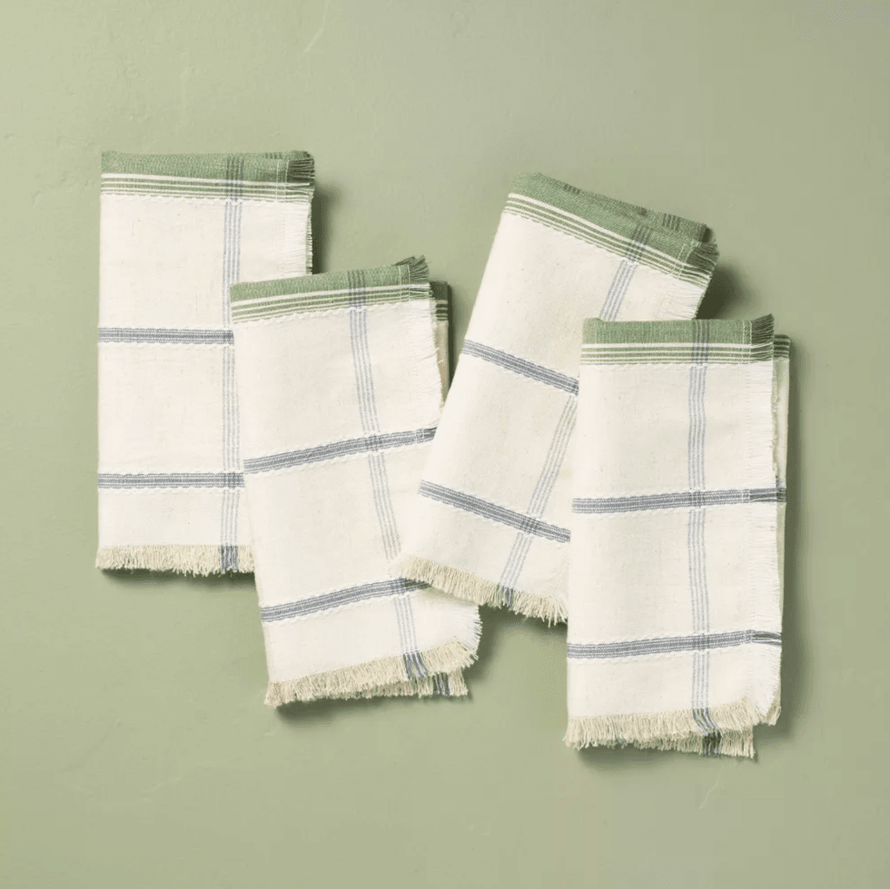 Four folded white napkins with green and blue stripes on a light green background.