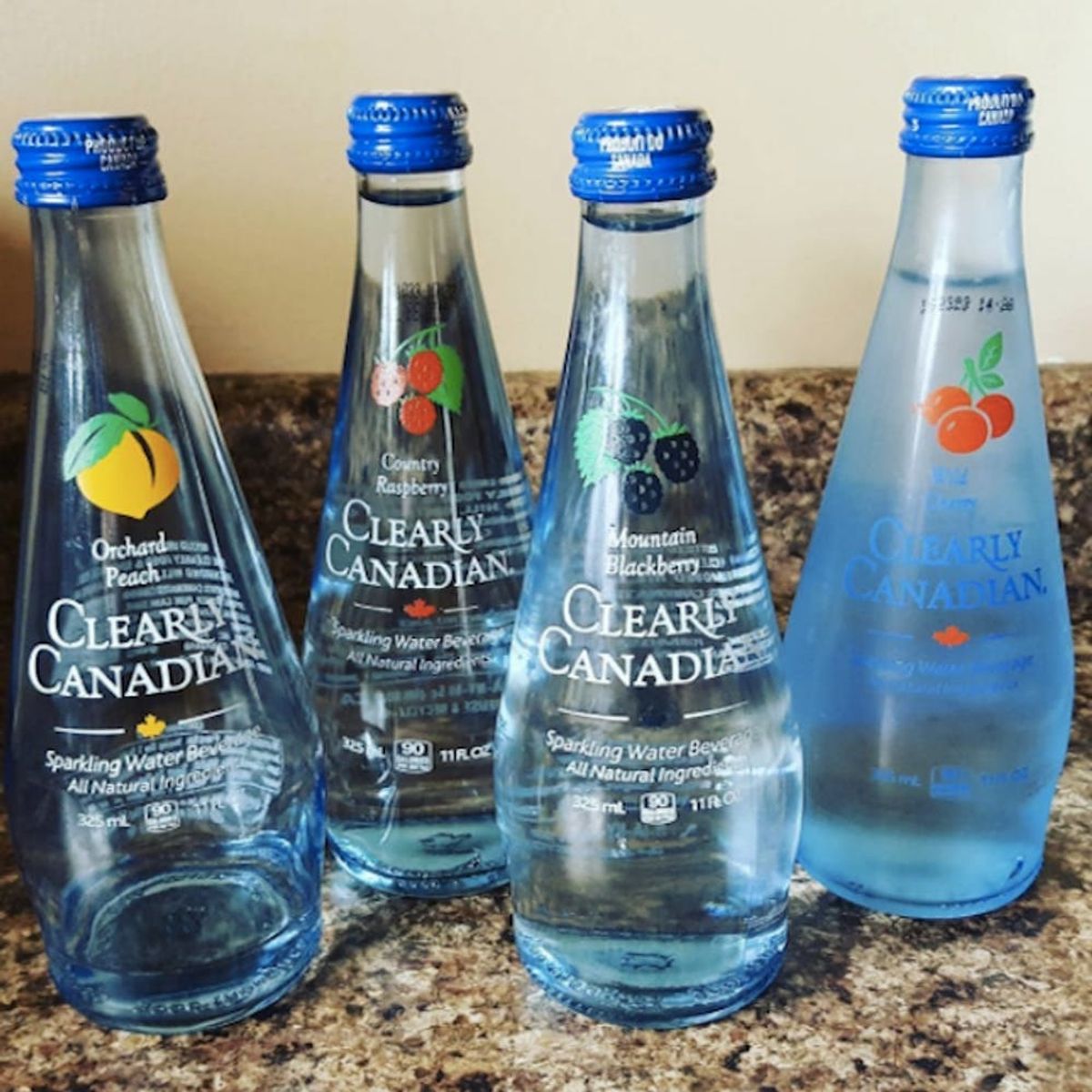 four glass bottles of Clearly Canadian including orchard peach, country raspberry, mountain blackberry and wild cherry