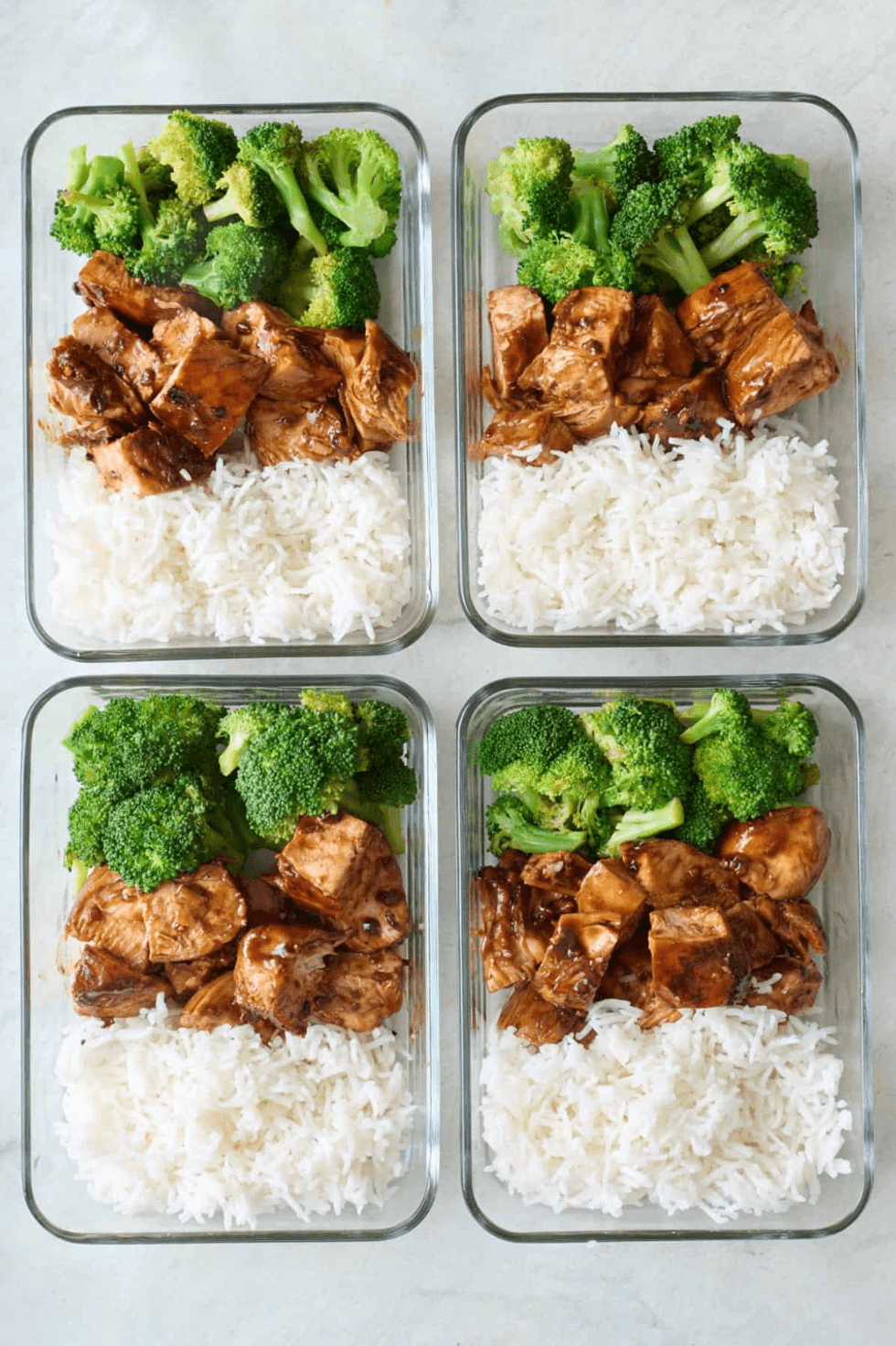 Four meal prep containers with broccoli, rice, and glazed chicken.