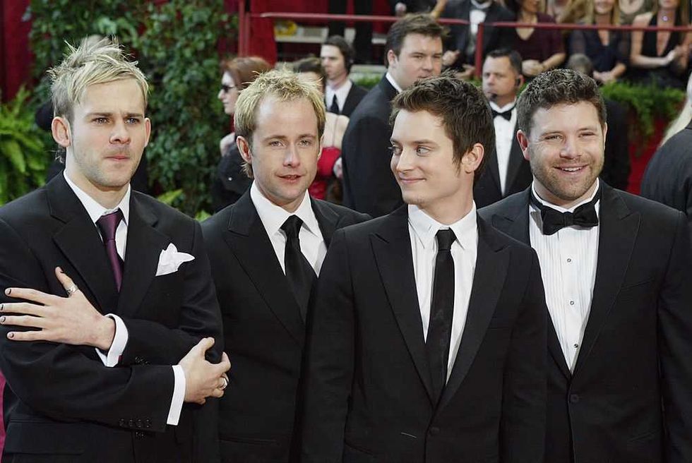 Four men in suits at a formal event, standing in a row, smiling and talking.