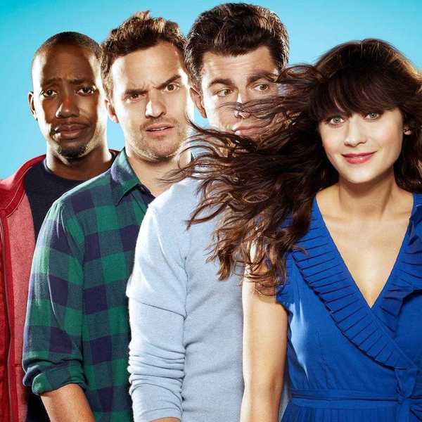 Four people standing together, smiling and wind blowing the woman's hair.