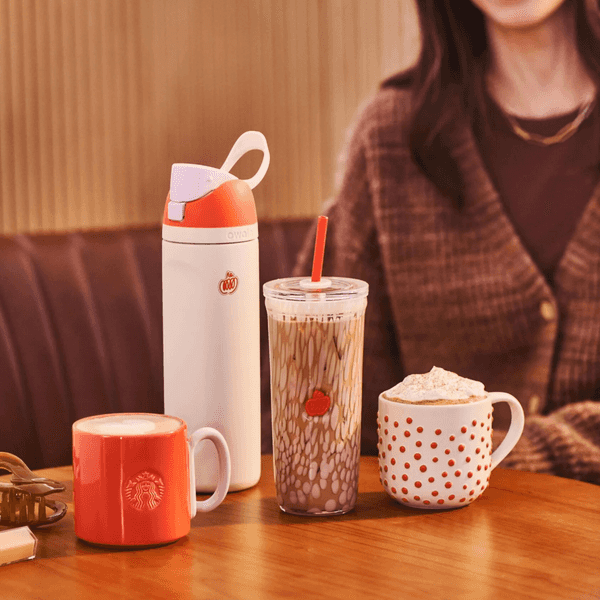 Four varied drinks on a wooden table, with a person sitting nearby.