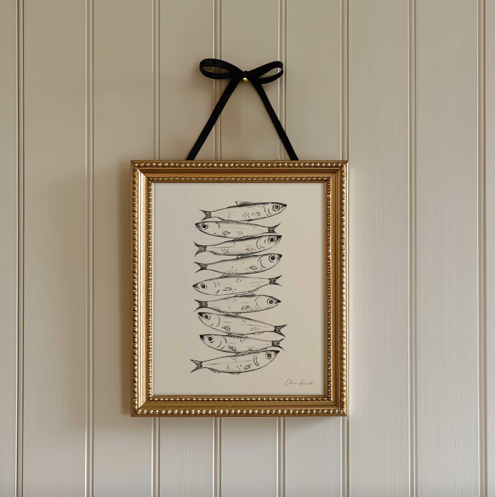Framed fish drawing, hung by a black ribbon on a paneled wall.