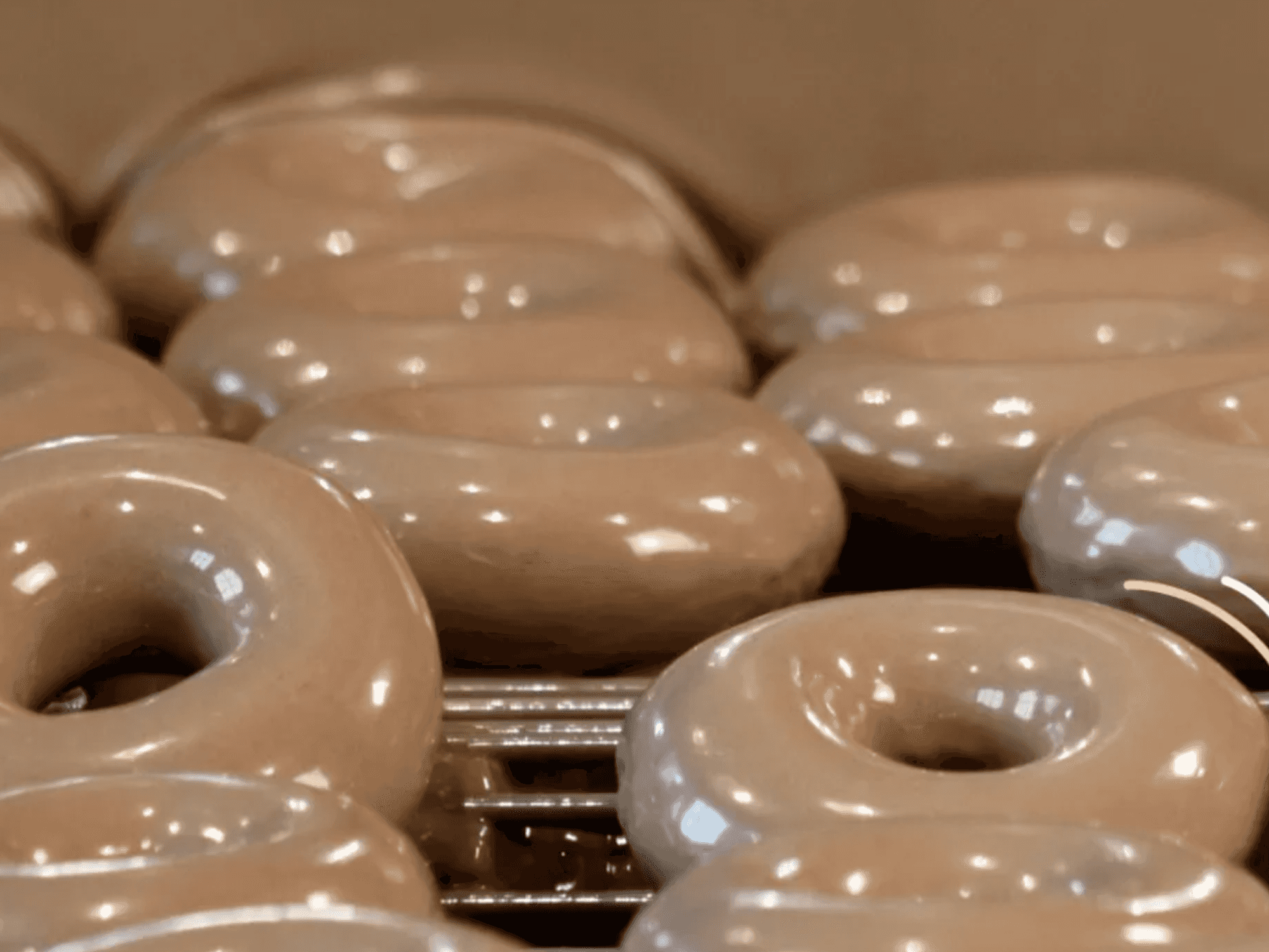 Freshly glazed donuts on a rack with decorative sparkle and line graphics.