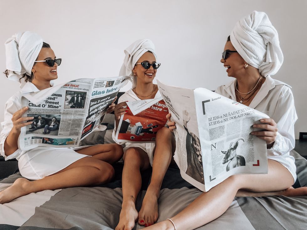 friends in robes while holding newspapers